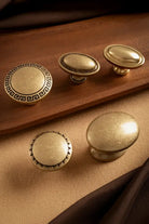 Antique brass cabinet knobs set with round tops and ornate Greek key rosette bases
