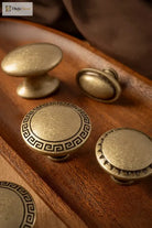 Antique brass cabinet knobs with round and oval tops, including a Greek key medallion base
