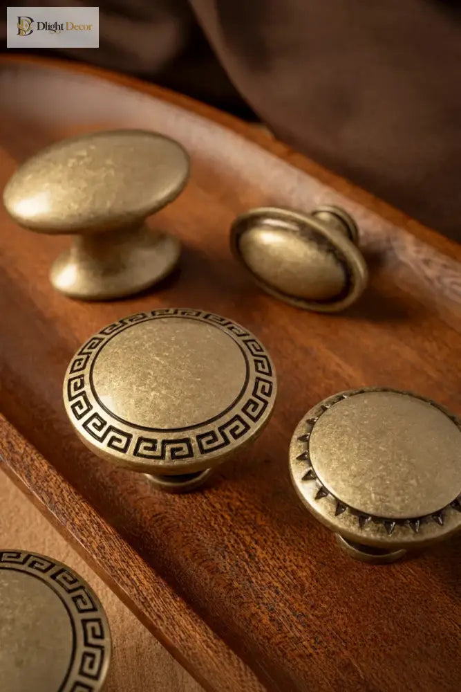 Antique brass cabinet knobs with round and oval tops, including a Greek key medallion base