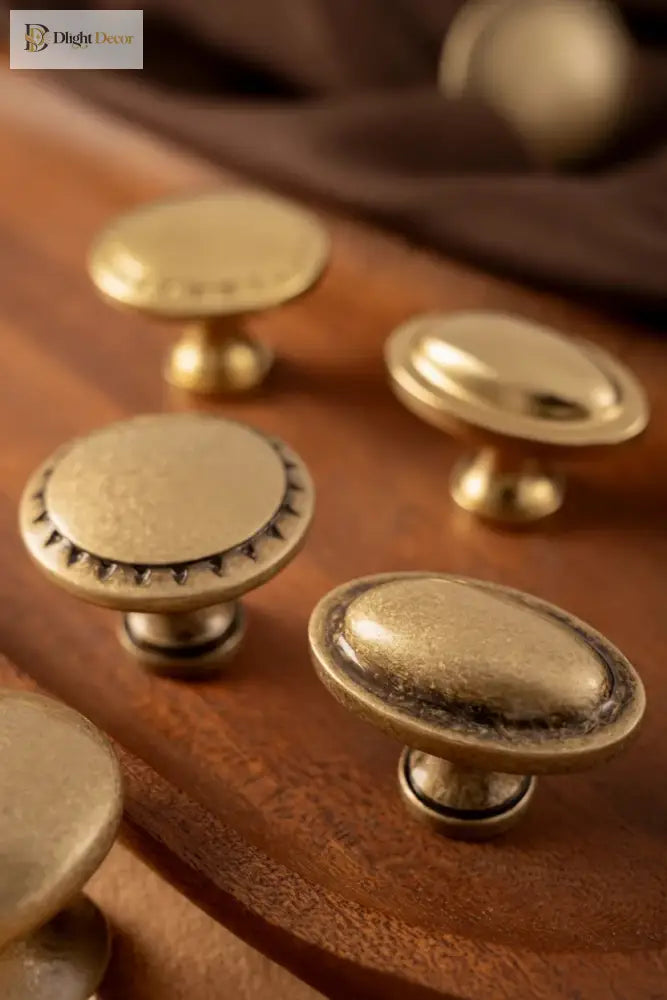 Antique brass cabinet knobs with round and oval forms, each with textured base detailing