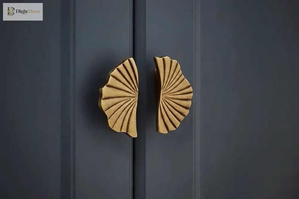 Ruffled cabinet handle pair in antique brass finish on dark cabinet doors.