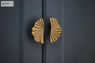 Ruffled cabinet handle pair in antique brass finish on dark cabinet doors.
