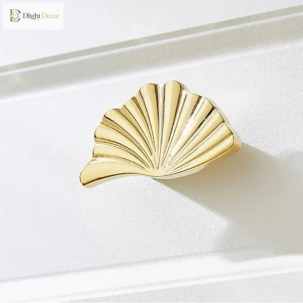 Single ruffled cabinet handle in PVD gold finish with fan-like ridges.
