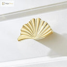 Single ruffled cabinet handle in PVD gold finish with fan-like ridges.