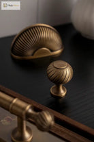 Brushed brass cabinet knob with ribbed shell dome and round base