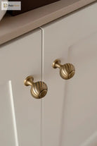 Brushed brass cabinet knobs with ribbed shell tops on front panel