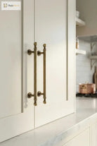 Brushed brass double T-bar cabinet pull on white cabinet door, wall-mounted handles