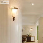Retro gold wall sconce with frosted glass shade and detailed metal leaf ornaments