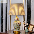 Floral ceramic lamp with pleated shade, gold pedestal base, and detailed bird motif.