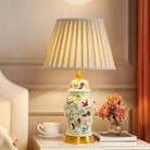 Floral ceramic desk lamp with gold base, bird-and-flower pattern, pleated shade.