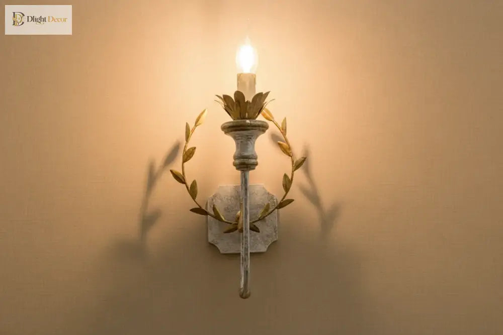 Gold and grey iron wall sconce with lit LED bulb and leaf wreath arms