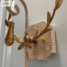 Close-up of gold leaf details and textured grey metal wall sconce backplate
