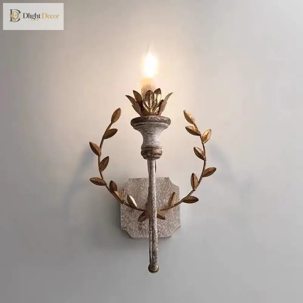 Grey metal wall sconce with warm LED flame bulb and circular gold leaf accents