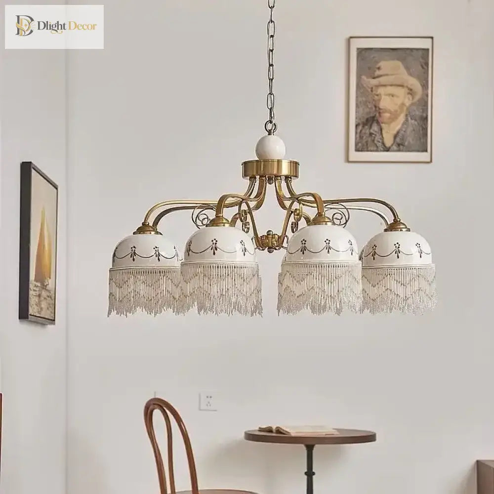 Gold multi-head pendant light with white ceramic shades, brown floral accents, tassel fringe on chain