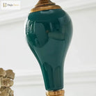 Close-up of green ceramic lamp base with glossy finish and gold metal collar