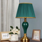 Green ceramic table lamp with pleated teal fabric shade and gold-trim base