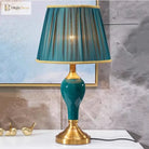 Green ceramic table lamp with pleated teal shade and gold base on a stand