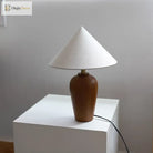 Wooden desk lamp with white cone shade and round brass-topped neck on white block