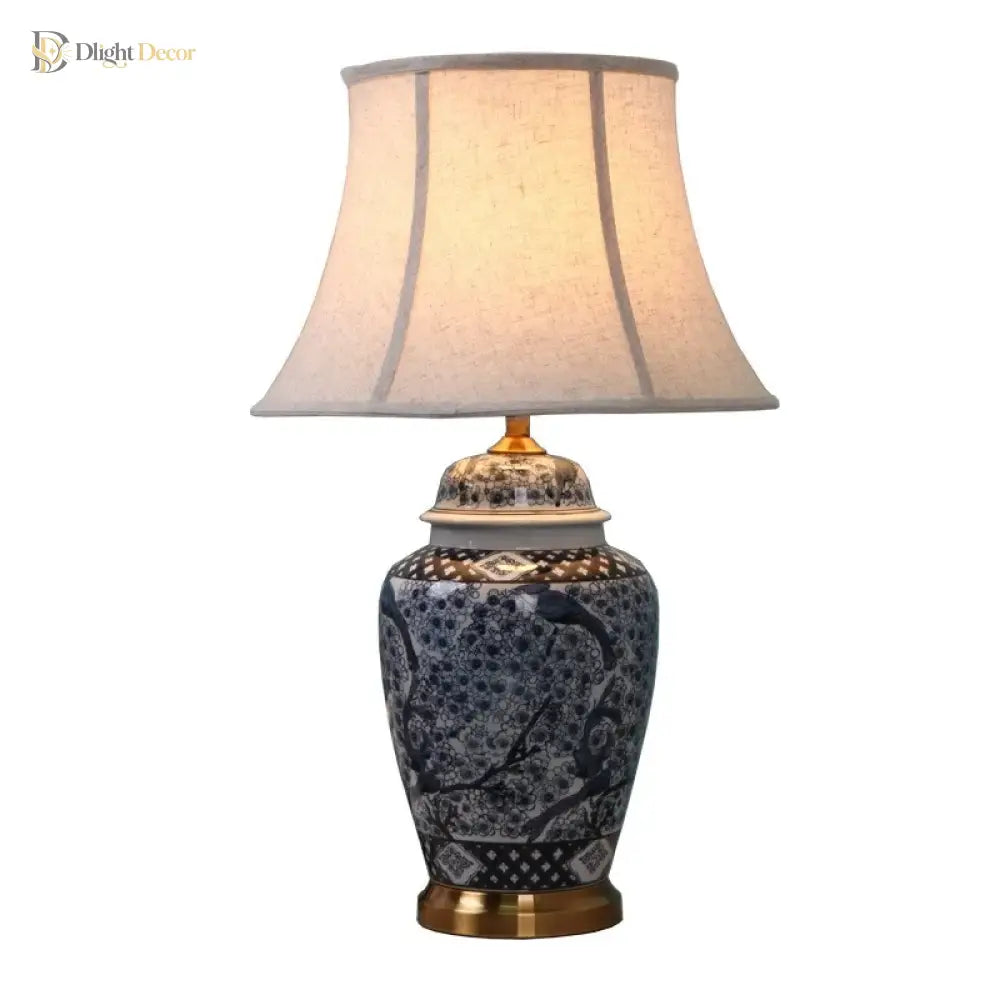 Blue indigo ceramic lamp with beige drum shade, gold finial, and gold base ring
