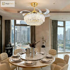 Gold ceiling fan with crystal glass light fixture and clear blades over dining table