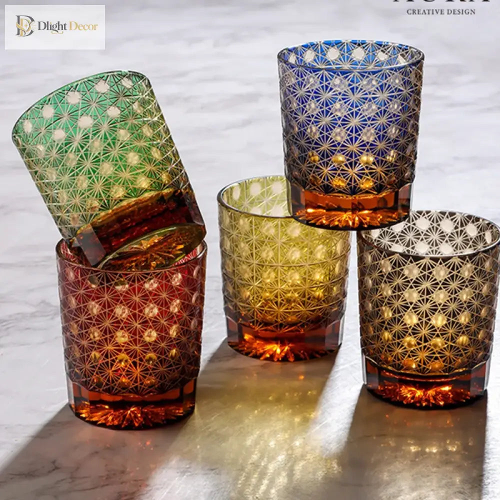 Set of three cut crystal whisky glasses with geometric patterns in green and amber tones