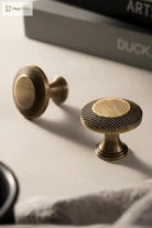 Antique brass cabinet knobs and a knurled grid bar pull on a drawer front.