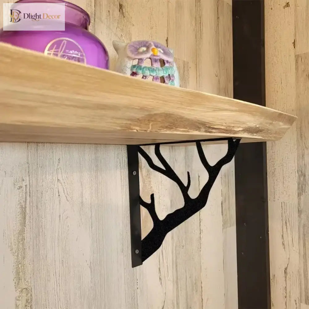 Black metal tree-branch wall bracket with screws, supporting a light wood shelf