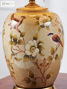 Close-up of ceramic lamp body with floral and bird pattern and gold neck