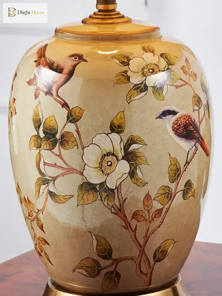 Close-up of ceramic lamp body with floral and bird pattern and gold neck