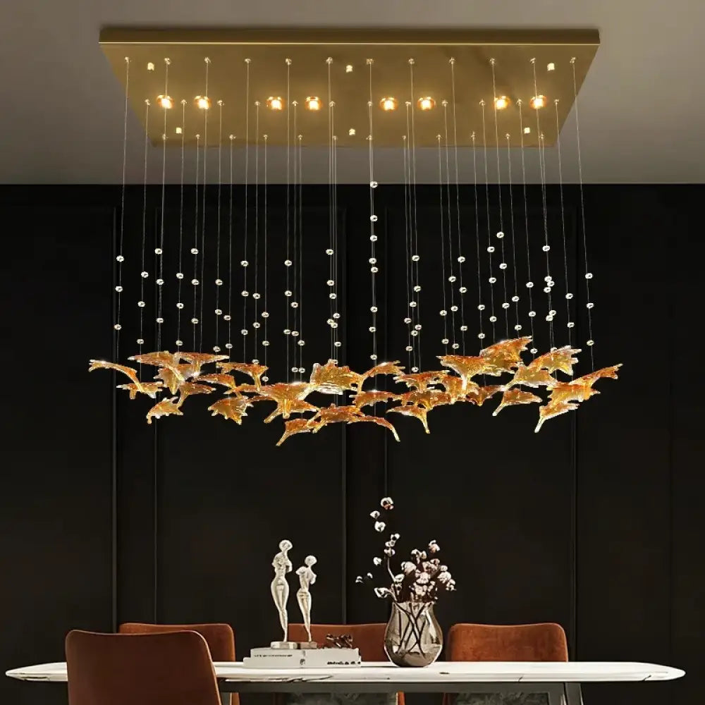 Gold glass pendant chandelier with hanging strands and warm bulbs above dining table