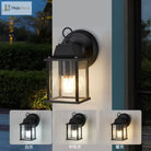 Black outdoor wall lantern light with clear glass sides and warm glowing bulb