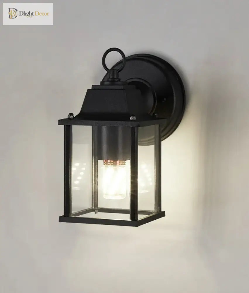 Black exterior wall sconce with clear glass lantern and warm light illumination