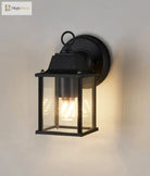 Black outdoor wall lantern light with clear glass panels and warm glowing bulb