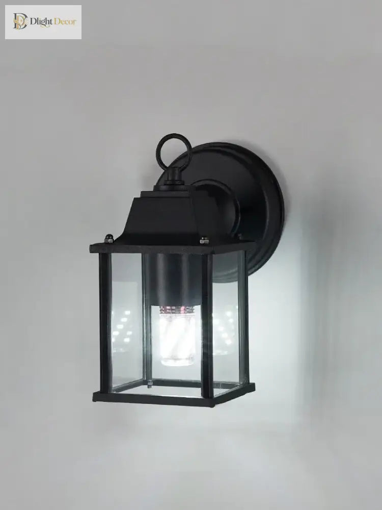 Black outdoor wall lantern light with clear glass and warm glowing bulb