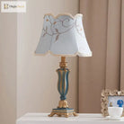 LED desk lamp with cream floral lampshade and teal-blue resin base with gold trim.