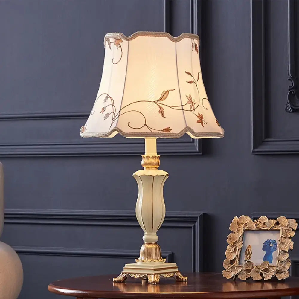 Cream floral fabric lampshade with gold edging on light gold resin table lamp base