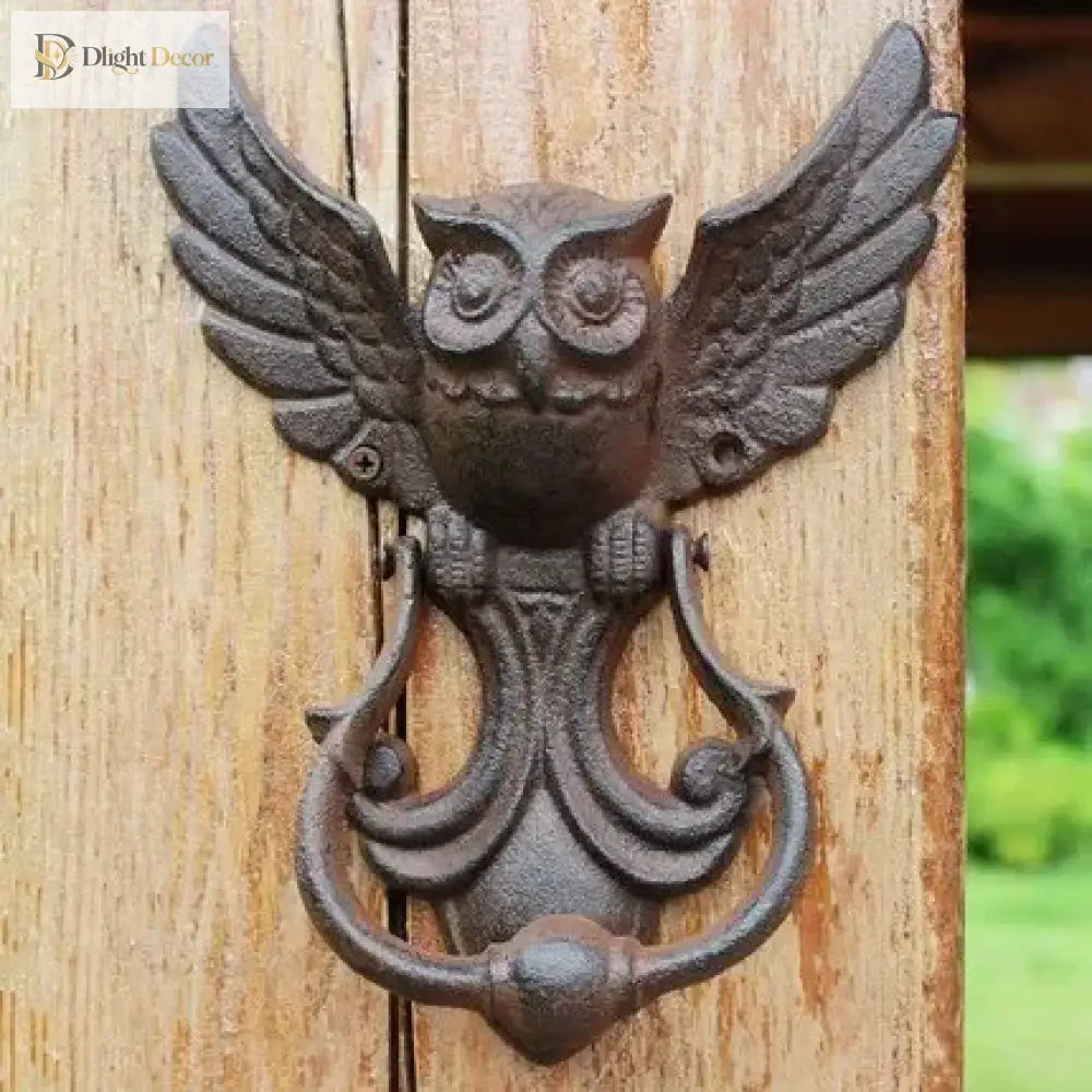 Cast iron owl door knocker with wing details and curved handle, on a wooden door