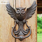 Cast iron owl door knocker, front view with wide wings and arched handhold on a door