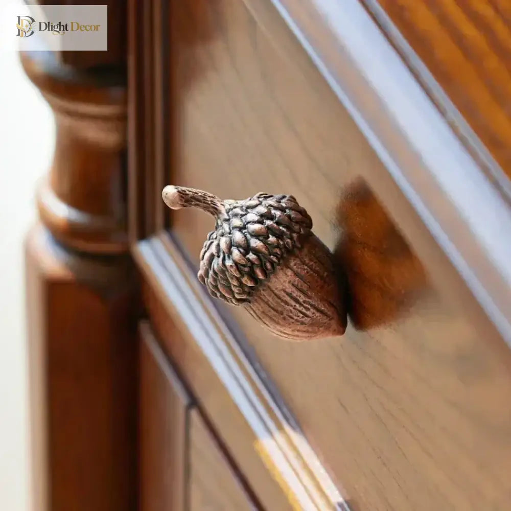 Zinc alloy acorn knob on a wooden drawer front, angled close-up