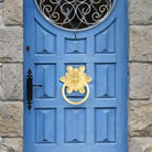 Gold-tone floral ring pull door knocker on a decorative cabinet door