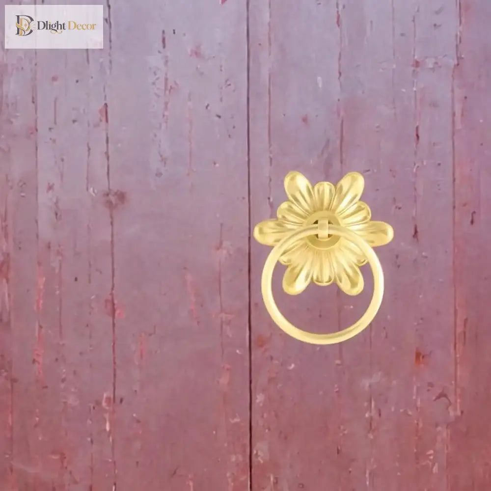 Gold-tone floral ring pull door knocker mounted on a door panel