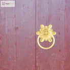 Gold-tone floral ring pull door knocker mounted on a door panel