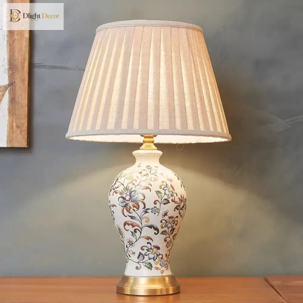 Floral ceramic table lamp with pleated white shade and brass base, front view