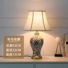 Floral ceramic table lamp with pleated white shade and brass base, angled front view
