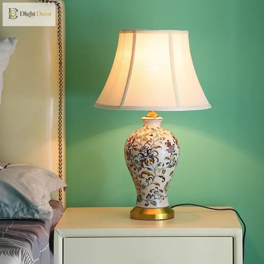 Floral ceramic table lamp with beige fabric shade and gold-toned base.