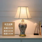 Floral ceramic table lamp front view with pleated cream shade and gold base.