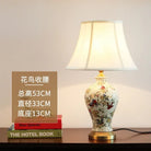 Floral ceramic table lamp with pleated cream shade, gold base, and side profile view.