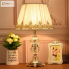 Crystal table lamp with pleated white shade and gold-trimmed base detail