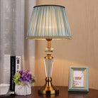 Gold and clear crystal LED table lamp with pleated teal fabric shade and finial base