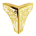 Gold-tone geometric metal furniture leg with cutout lattice design, corner view